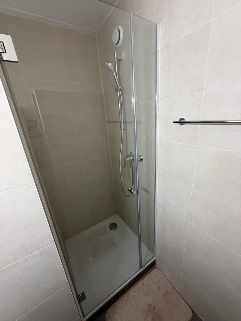 Paroi fixe sur profils chromés et porte de douche fermée avec joint magnétique