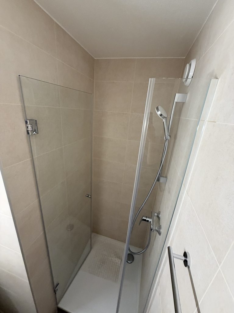 Porte de douche ouverte et partie fixe sur profils chromés